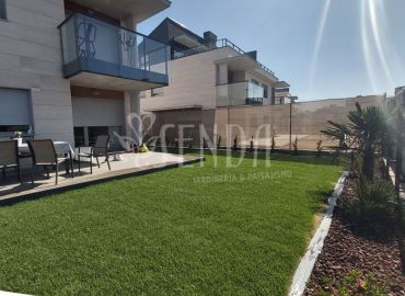 Jardín residencial con pradera verde, terraza y vegetación ornamental